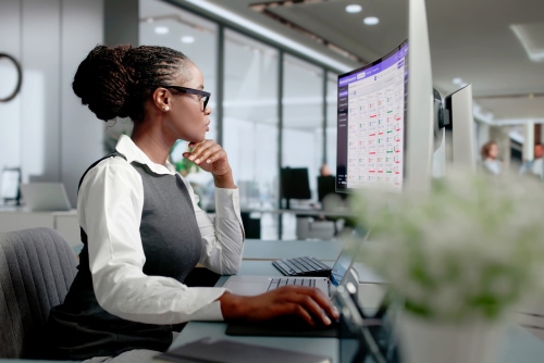 Woman working on desktop computer managing membership database software in office
